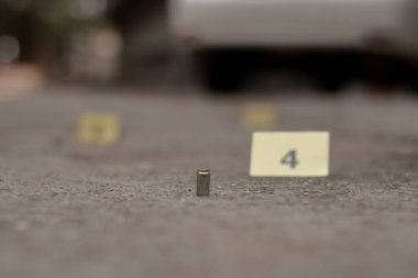 Tabanca mermisi çimento zemininde bulanık sarı kağıt ve sigara filtresi kalıntıları, polis memurları ve yatırımcılar tarafından soruşturma ve suç konsepti, yumuşak odaklı.