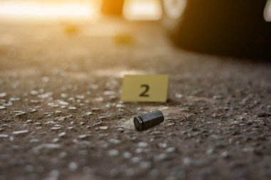 Tabanca mermisi çimento zemininde bulanık sarı kağıt ve sigara filtresi kalıntıları, polis memurları ve yatırımcılar tarafından soruşturma ve suç konsepti, yumuşak odaklı.