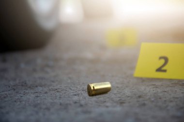 Tabanca mermisi çimento zemininde bulanık sarı kağıt ve sigara filtresi kalıntıları, polis memurları ve yatırımcılar tarafından soruşturma ve suç konsepti, yumuşak odaklı.