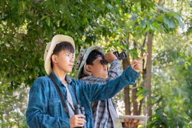 Yaz kampı sırasında tropikal ormanda kuş gözlemlemek için dürbün kullanan Asyalı çocuklar, sınıfın dışında yaşayan canlıları, vahşi hayvanları ve böcekleri öğrenme fikri.
