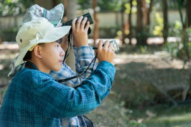 Yaz kampı sırasında tropikal ormanda kuş gözlemlemek için dürbün kullanan Asyalı çocuklar, sınıfın dışında yaşayan canlıları, vahşi hayvanları ve böcekleri öğrenme fikri.