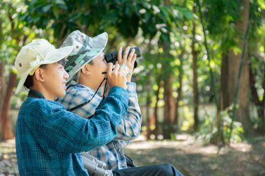 Yaz kampı sırasında tropikal ormanda kuş gözlemlemek için dürbün kullanan Asyalı çocuklar, sınıfın dışında yaşayan canlıları, vahşi hayvanları ve böcekleri öğrenme fikri.