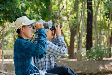 Yaz kampı sırasında tropikal ormanda kuş gözlemlemek için dürbün kullanan Asyalı çocuklar, sınıfın dışında yaşayan canlıları, vahşi hayvanları ve böcekleri öğrenme fikri.