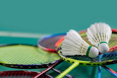 Badminton spor malzemeleri, mekik horozları ve raketler, kapalı badminton kortunun pv zeminine yerleştirilmiş, yumuşak odaklı.