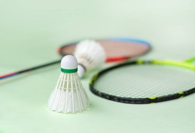 Badminton spor malzemeleri, raketler ve açık yeşil zemine yerleştirilmiş beyaz tüylü mekikçikler..