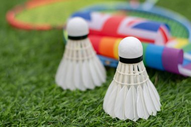 Beyaz Krem Mekik, badminton spor ekipmanları, İngiliz ulusal bayrağı ve gökkuşağı bayrağının önündeki yeşil çimlere yerleştirilmiş yerler, tüm cinsiyetler ve lgbtq + insanları için badminton sporu kavramı.