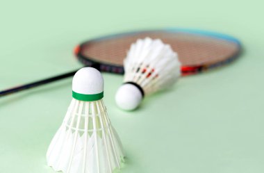 Badminton spor malzemeleri, raketler ve açık yeşil zemine yerleştirilmiş beyaz tüylü mekikçikler..