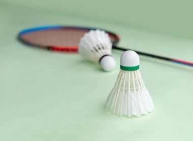 Badminton spor malzemeleri, raketler ve açık yeşil zemine yerleştirilmiş beyaz tüylü mekikçikler..