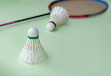 Badminton spor malzemeleri, raketler ve açık yeşil zemine yerleştirilmiş beyaz tüylü mekikçikler..