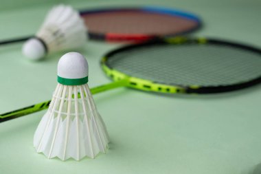 Badminton spor malzemeleri, raketler ve açık yeşil zemine yerleştirilmiş beyaz tüylü mekikçikler..