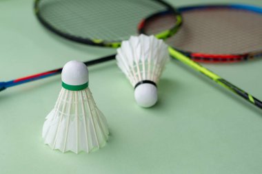 Badminton spor malzemeleri, raketler ve açık yeşil zemine yerleştirilmiş beyaz tüylü mekikçikler..