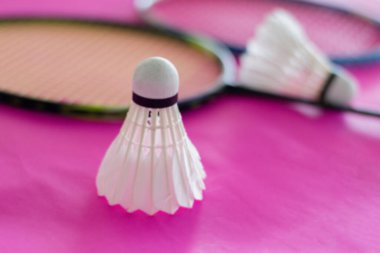 Badminton mekik penislerinin bulanık görüntüsü ve pembe kağıt üzerindeki raketler, badminton spor aşığı kavramı.