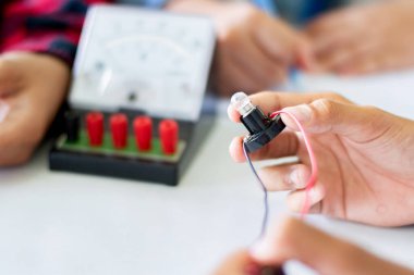 Fizik bilimi dersinde küçük bir elektrik sayacı ve küçük bir fener ampulü kullanarak öğrencilerin elektrik devreleri üzerinde yapılan çalışmalar..