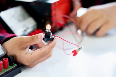 Fizik bilimi dersinde küçük bir elektrik sayacı ve küçük bir fener ampulü kullanarak öğrencilerin elektrik devreleri üzerinde yapılan çalışmalar..