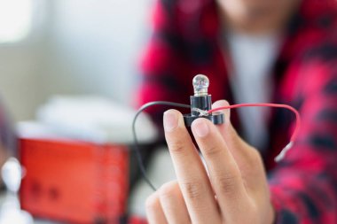 Fizik bilimi dersinde küçük bir elektrik sayacı ve küçük bir fener ampulü kullanarak öğrencilerin elektrik devreleri üzerinde yapılan çalışmalar..