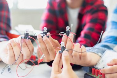 Fizik bilimi dersinde küçük bir elektrik sayacı ve küçük bir fener ampulü kullanarak öğrencilerin elektrik devreleri üzerinde yapılan çalışmalar..