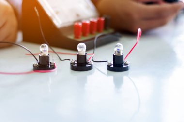 Fizik bilimi dersinde küçük bir elektrik sayacı ve küçük bir fener ampulü kullanarak öğrencilerin elektrik devreleri üzerinde yapılan çalışmalar..