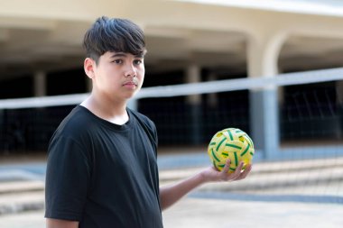 Sepak takunyalı top, Güneydoğu Asya ülkeleri geleneksel spor, genç sepak takham oyuncusunu kalenin önünde tutarken topu başka bir oyuncuya atıyor..