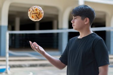 Sepak takunyalı top, Güneydoğu Asya ülkeleri geleneksel spor, genç sepak takham oyuncusunu kalenin önünde tutarken topu başka bir oyuncuya atıyor..