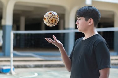 Sepak takunyalı top, Güneydoğu Asya ülkeleri geleneksel spor, genç sepak takham oyuncusunu kalenin önünde tutarken topu başka bir oyuncuya atıyor..