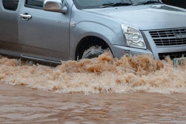 Şiddetli yağışlı bir mevsim nedeniyle çamurlu yağmurlar bölgeyi birbirine bağlayan ana yolları sular altında bıraktı, arabaların geçmesini zorlaştırdı ve motor arızalarına yol açtı, hareket halinde, araba sigortası konsepti, hareket halinde.