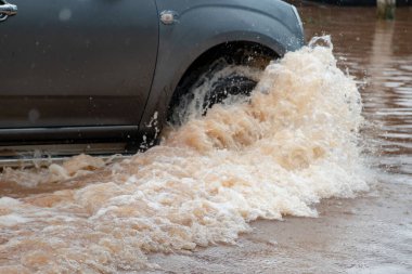 Şiddetli yağışlı bir mevsim nedeniyle çamurlu yağmurlar bölgeyi birbirine bağlayan ana yolları sular altında bıraktı, arabaların geçmesini zorlaştırdı ve motor arızalarına yol açtı, hareket halinde, araba sigortası konsepti, hareket halinde.