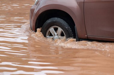 Şiddetli yağışlı bir mevsim nedeniyle çamurlu yağmurlar bölgeyi birbirine bağlayan ana yolları sular altında bıraktı, arabaların geçmesini zorlaştırdı ve motor arızalarına yol açtı, hareket halinde, araba sigortası konsepti, hareket halinde.