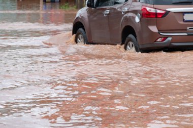 Şiddetli yağışlı bir mevsim nedeniyle çamurlu yağmurlar bölgeyi birbirine bağlayan ana yolları sular altında bıraktı, arabaların geçmesini zorlaştırdı ve motor arızalarına yol açtı, hareket halinde, araba sigortası konsepti, hareket halinde.