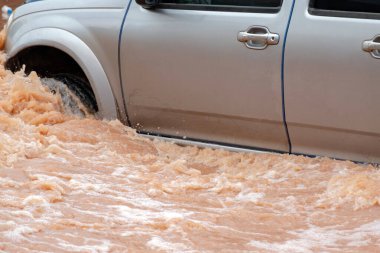 Şiddetli yağışlı bir mevsim nedeniyle çamurlu yağmurlar bölgeyi birbirine bağlayan ana yolları sular altında bıraktı, arabaların geçmesini zorlaştırdı ve motor arızalarına yol açtı, hareket halinde, araba sigortası konsepti, hareket halinde.