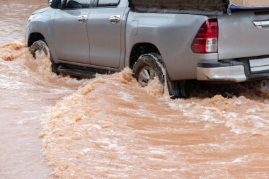 Şiddetli yağışlı bir mevsim nedeniyle çamurlu yağmurlar bölgeyi birbirine bağlayan ana yolları sular altında bıraktı, arabaların geçmesini zorlaştırdı ve motor arızalarına yol açtı, hareket halinde, araba sigortası konsepti, hareket halinde.