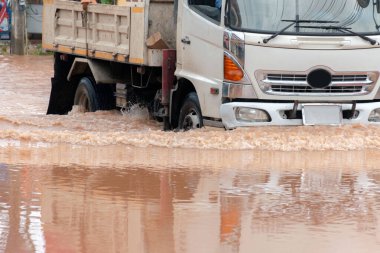 Şiddetli yağışlı bir mevsim nedeniyle çamurlu yağmurlar bölgeyi birbirine bağlayan ana yolları sular altında bıraktı, arabaların geçmesini zorlaştırdı ve motor arızalarına yol açtı, hareket halinde, araba sigortası konsepti, hareket halinde.