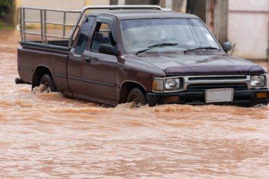 Şiddetli yağışlı bir mevsim nedeniyle çamurlu yağmurlar bölgeyi birbirine bağlayan ana yolları sular altında bıraktı, arabaların geçmesini zorlaştırdı ve motor arızalarına yol açtı, hareket halinde, araba sigortası konsepti, hareket halinde.