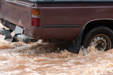 Şiddetli yağışlı bir mevsim nedeniyle çamurlu yağmurlar bölgeyi birbirine bağlayan ana yolları sular altında bıraktı, arabaların geçmesini zorlaştırdı ve motor arızalarına yol açtı, hareket halinde, araba sigortası konsepti, hareket halinde.