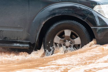 Şiddetli yağışlı bir mevsim nedeniyle çamurlu yağmurlar bölgeyi birbirine bağlayan ana yolları sular altında bıraktı, arabaların geçmesini zorlaştırdı ve motor arızalarına yol açtı, hareket halinde, araba sigortası konsepti, hareket halinde.