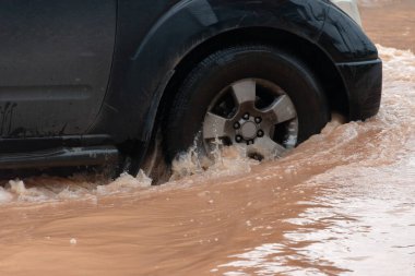 Şiddetli yağışlı bir mevsim nedeniyle çamurlu yağmurlar bölgeyi birbirine bağlayan ana yolları sular altında bıraktı, arabaların geçmesini zorlaştırdı ve motor arızalarına yol açtı, hareket halinde, araba sigortası konsepti, hareket halinde.