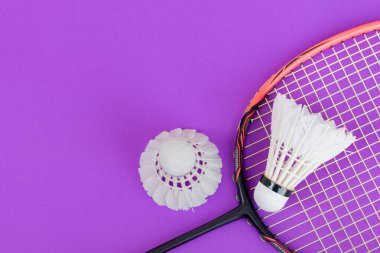 Badminton spor malzemeleri, raket ve beyaz krem rengi mekiks tüyü top kırmızı zeminde, yumuşak ve seçici odaklanma.
