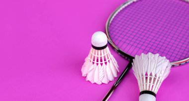 Badminton spor ekipmanları, raket ve beyaz krema, menekşe zemininde tüy yumağı, yumuşak ve seçici odaklanma.