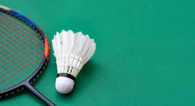 Badminton spor malzemeleri, raket ve beyaz krem rengi mekiks tüyü top yeşil zeminde, yumuşak ve seçici odaklı..