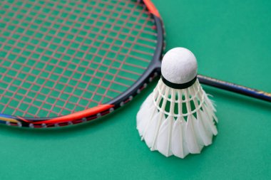 Badminton spor malzemeleri, raket ve beyaz krem rengi mekiks tüyü top yeşil zeminde, yumuşak ve seçici odaklı..