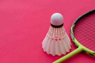 Badminton spor malzemeleri, raket ve beyaz krem rengi mekiks tüyü top kırmızı zeminde, yumuşak ve seçici odaklanma.