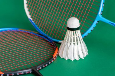 Badminton spor ekipmanları, raket ve beyaz krem rengi mekiks tüyü top yerde, yumuşak ve seçici odaklanma.