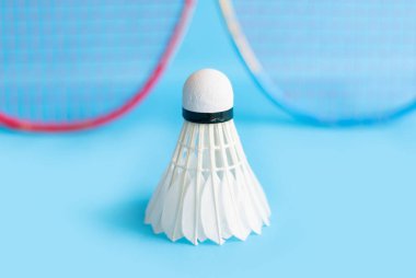 Badminton spor ekipmanları, raket ve beyaz krem rengi mekiks tüyü top yerde, yumuşak ve seçici odaklanma.