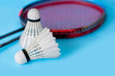 Badminton spor ekipmanları, raket ve beyaz krem rengi mekiks tüyü top yerde, yumuşak ve seçici odaklanma.