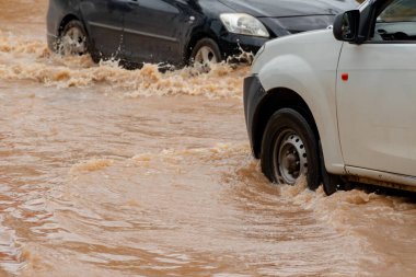 Şiddetli yağmurun yol açtığı sel basmış yollarda farklı türde arabalar sürülüyor. Su basmış yollarda araba sigortası ve dikkatli sürüş fikirleri.