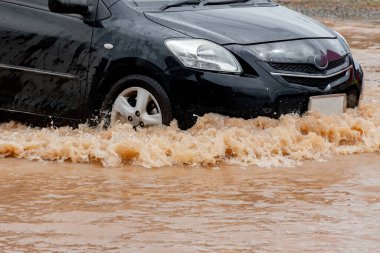 Şiddetli yağmurun yol açtığı sel basmış yollarda farklı türde arabalar sürülüyor. Su basmış yollarda araba sigortası ve dikkatli sürüş fikirleri.