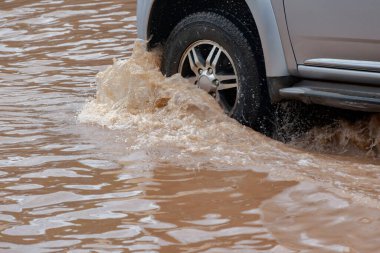 Şiddetli yağmurun yol açtığı sel basmış yollarda farklı türde arabalar sürülüyor. Su basmış yollarda araba sigortası ve dikkatli sürüş fikirleri.