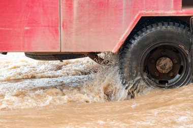 Şiddetli yağmurun yol açtığı sel basmış yollarda farklı türde arabalar sürülüyor. Su basmış yollarda araba sigortası ve dikkatli sürüş fikirleri.