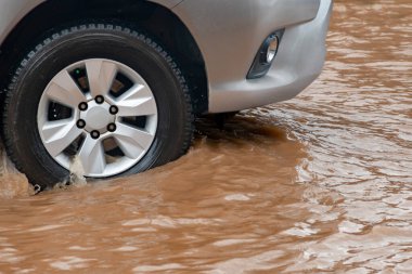 Şiddetli yağmurun yol açtığı sel basmış yollarda farklı türde arabalar sürülüyor. Su basmış yollarda araba sigortası ve dikkatli sürüş fikirleri.