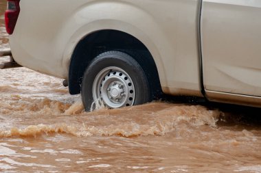 Şiddetli yağmurun yol açtığı sel basmış yollarda farklı türde arabalar sürülüyor. Su basmış yollarda araba sigortası ve dikkatli sürüş fikirleri.