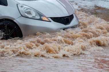 Şiddetli yağmurun yol açtığı sel basmış yollarda farklı türde arabalar sürülüyor. Su basmış yollarda araba sigortası ve dikkatli sürüş fikirleri.